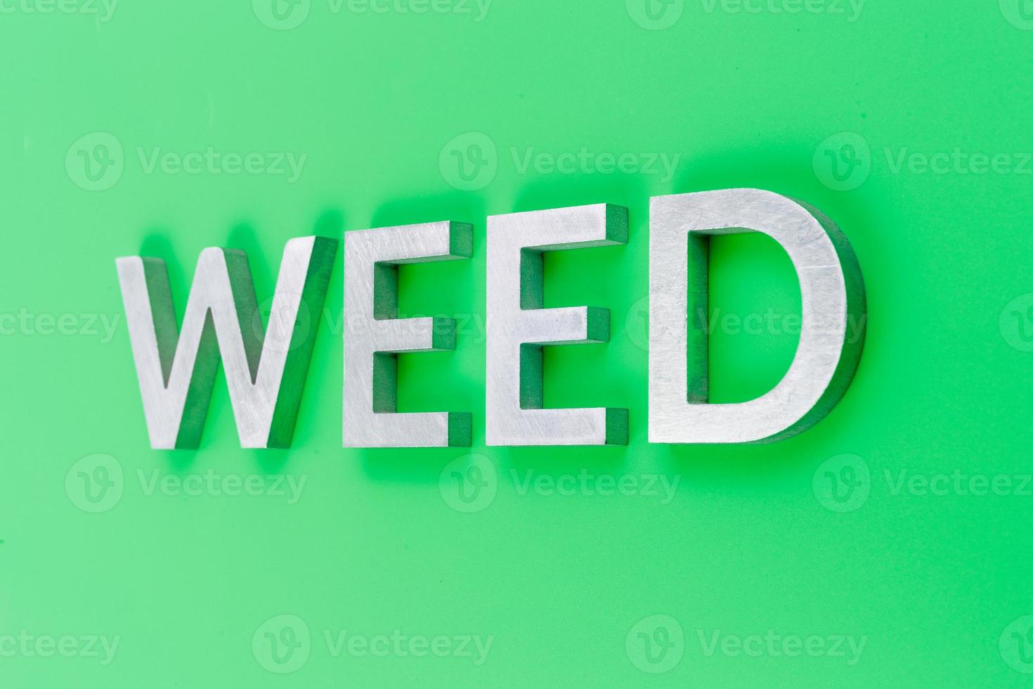 the word weed laid with silver metal letters on pastel green background with linear perspective photo