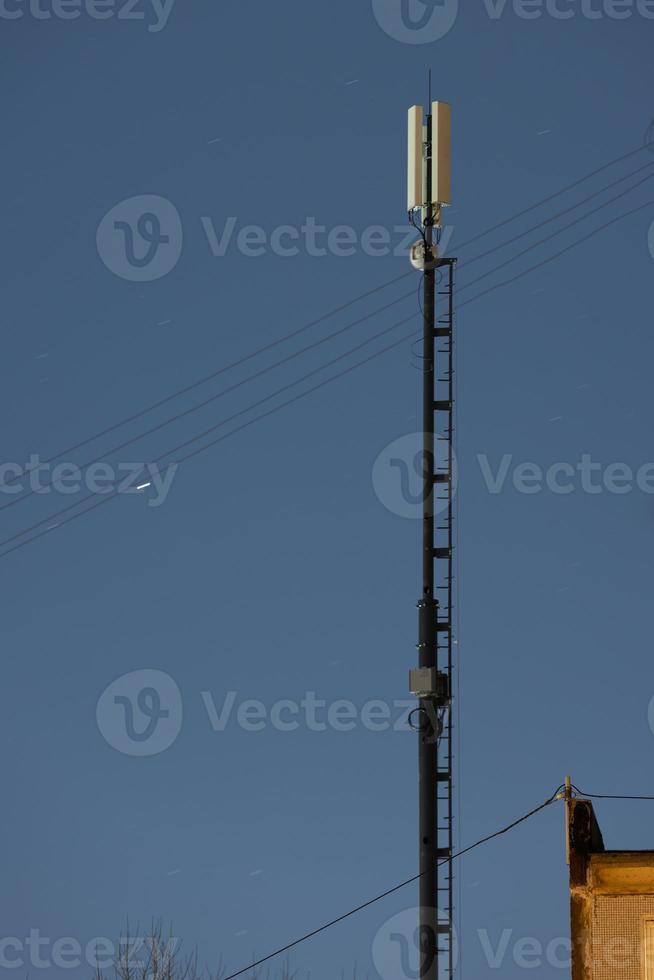 long lightweight internet telecommunication pipe tower with 4g and 5g transmitters at night photo