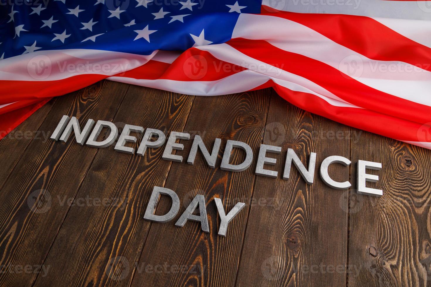 the words independence day laid on brown wooden planks surface with crumpled united states of america flag photo