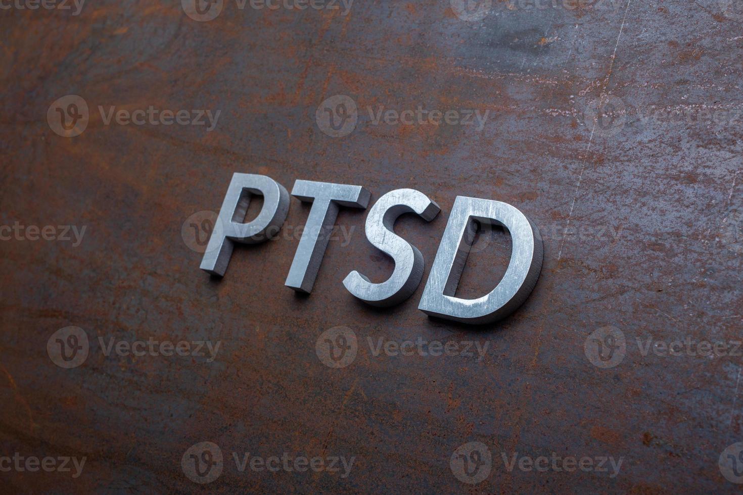 the word PTSD laid with silver metal letters on flat rusted steel sheet background in slanted diagonal perspective photo
