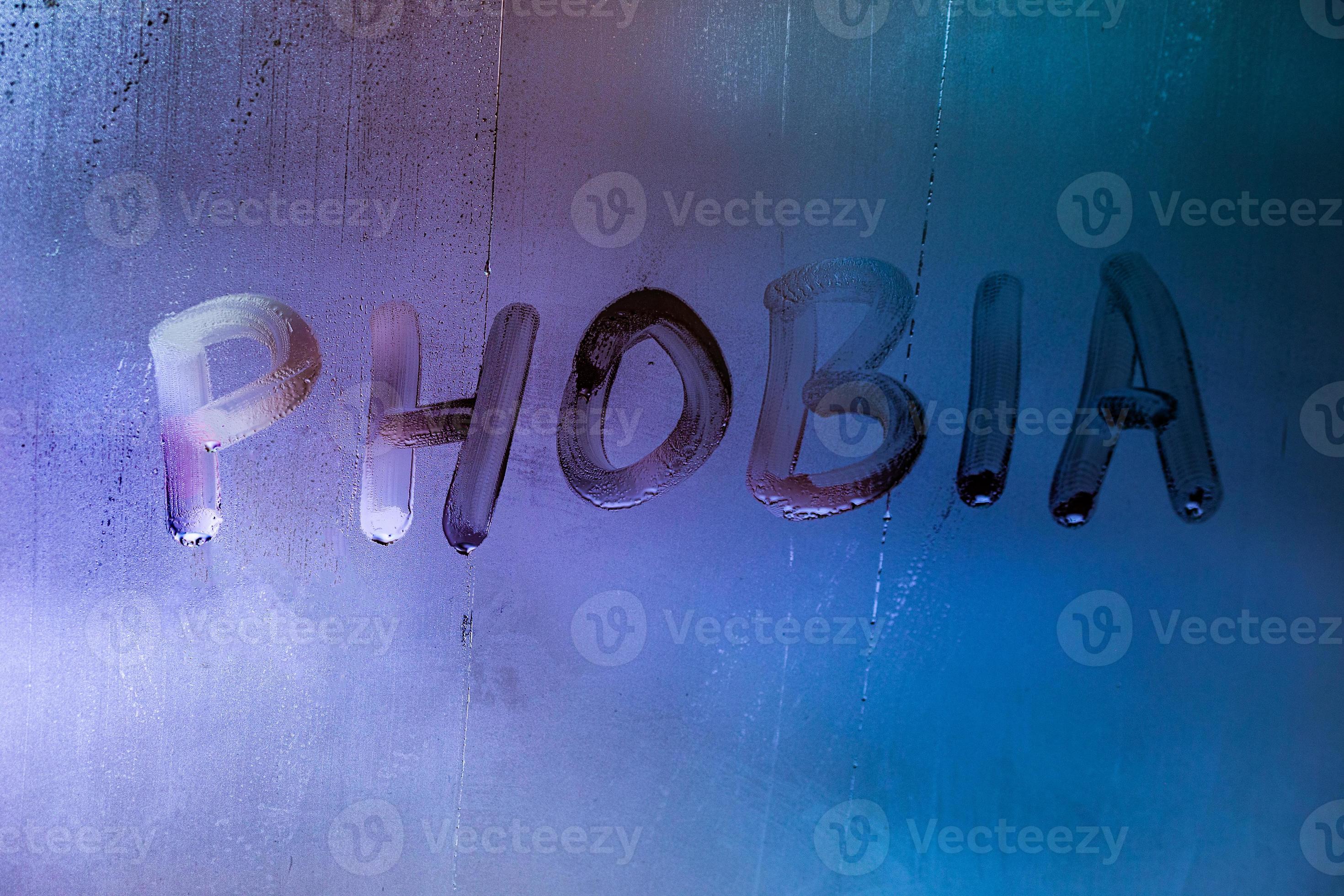 the word phobia handwritten on wet foggy window glass surface with blue
