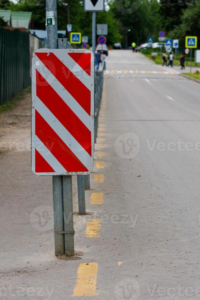 red and white diagonal striped sign at road fence end photo