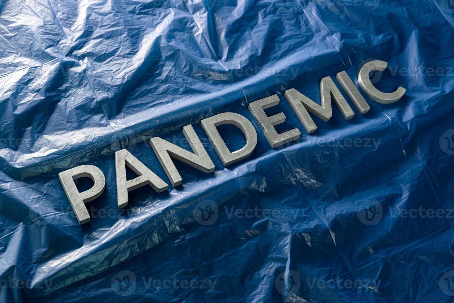 the word pandemic laid with silver letters on crumpled blue plastic film - diagonal perspective composition with selective focus photo