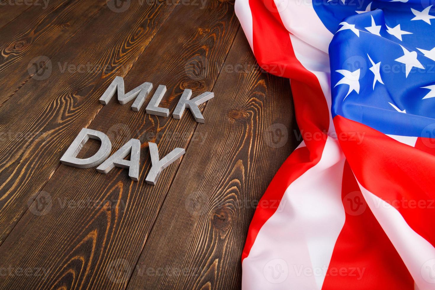 the word MLK day laid with silver metal letters on wooden surface with crumpled USA flag at right side photo