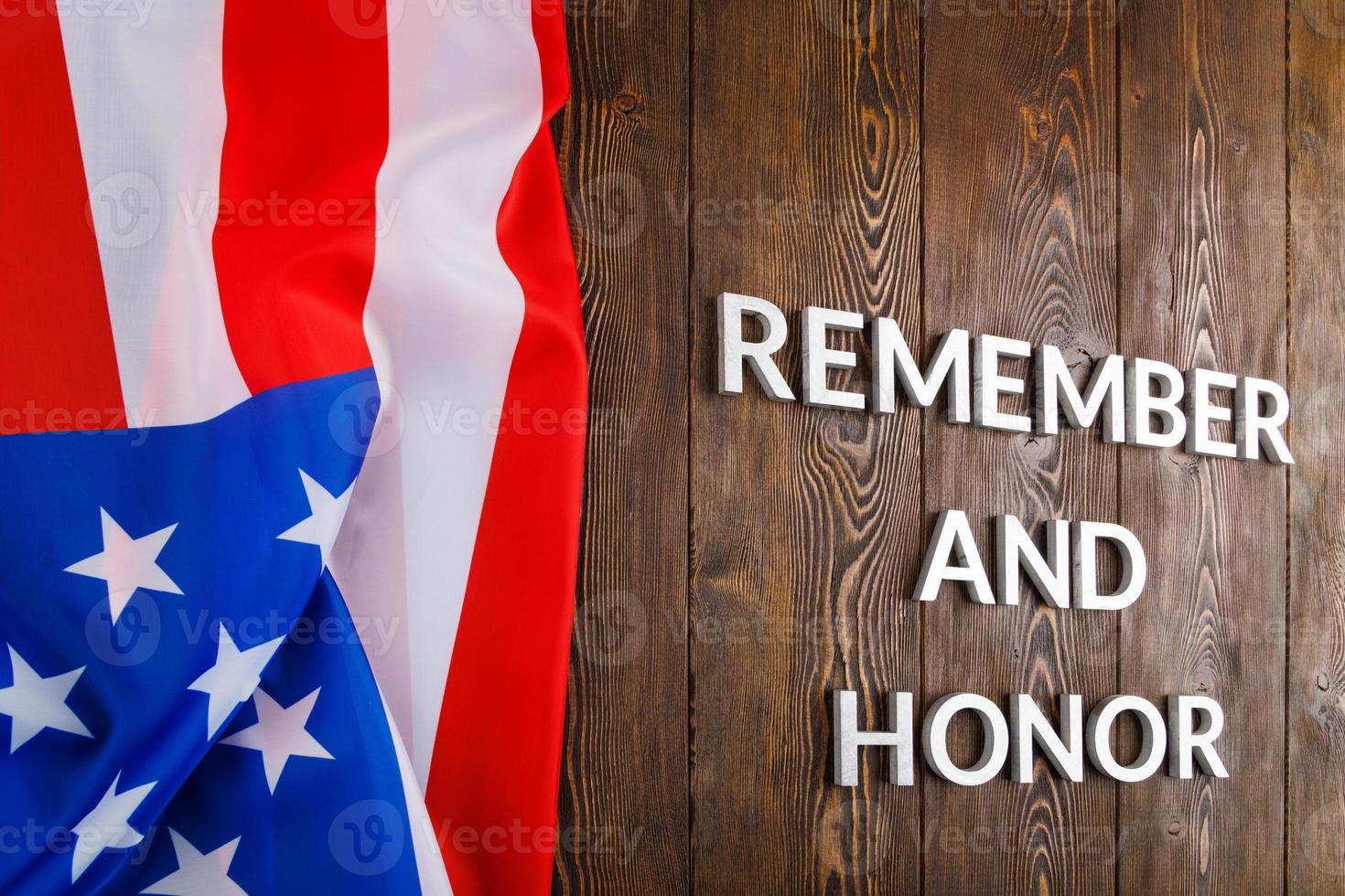 words remember and honor laid with silver metal letters on wooden background with USA flag on the left side photo