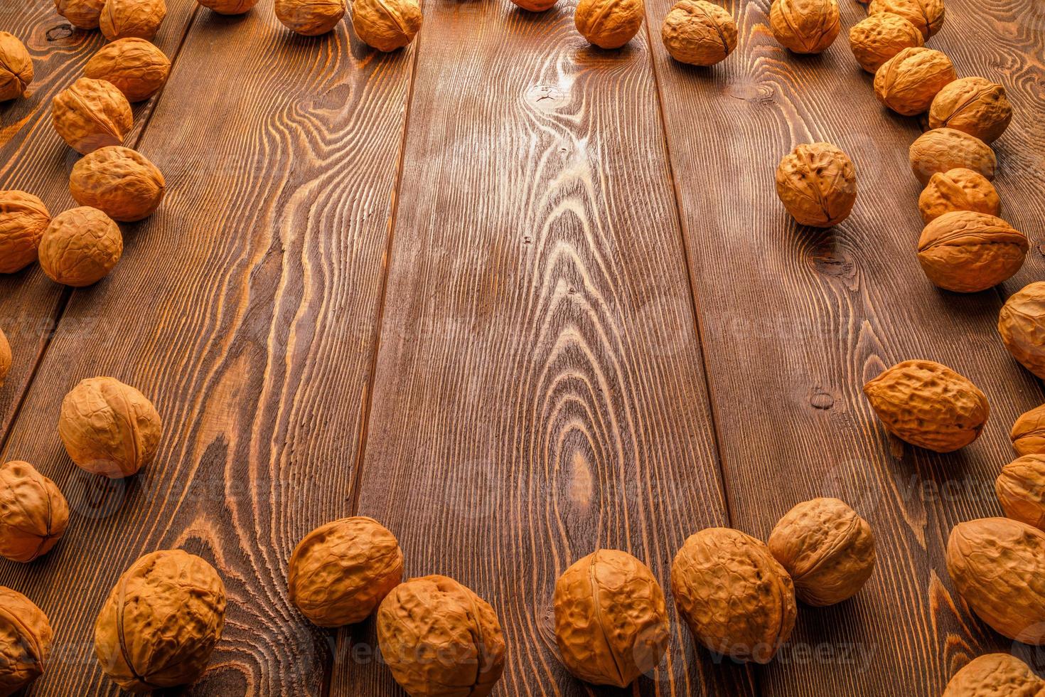 muchas nueces con cáscaras esparcidas en forma de marco rectangular sobre una superficie de madera marrón foto