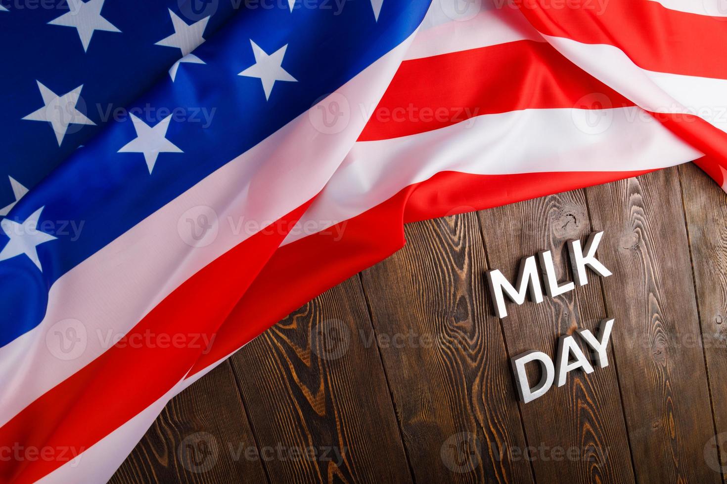 the word MLK day laid with silver metal letters on wooden surface with crumpled USA flag at upper side photo