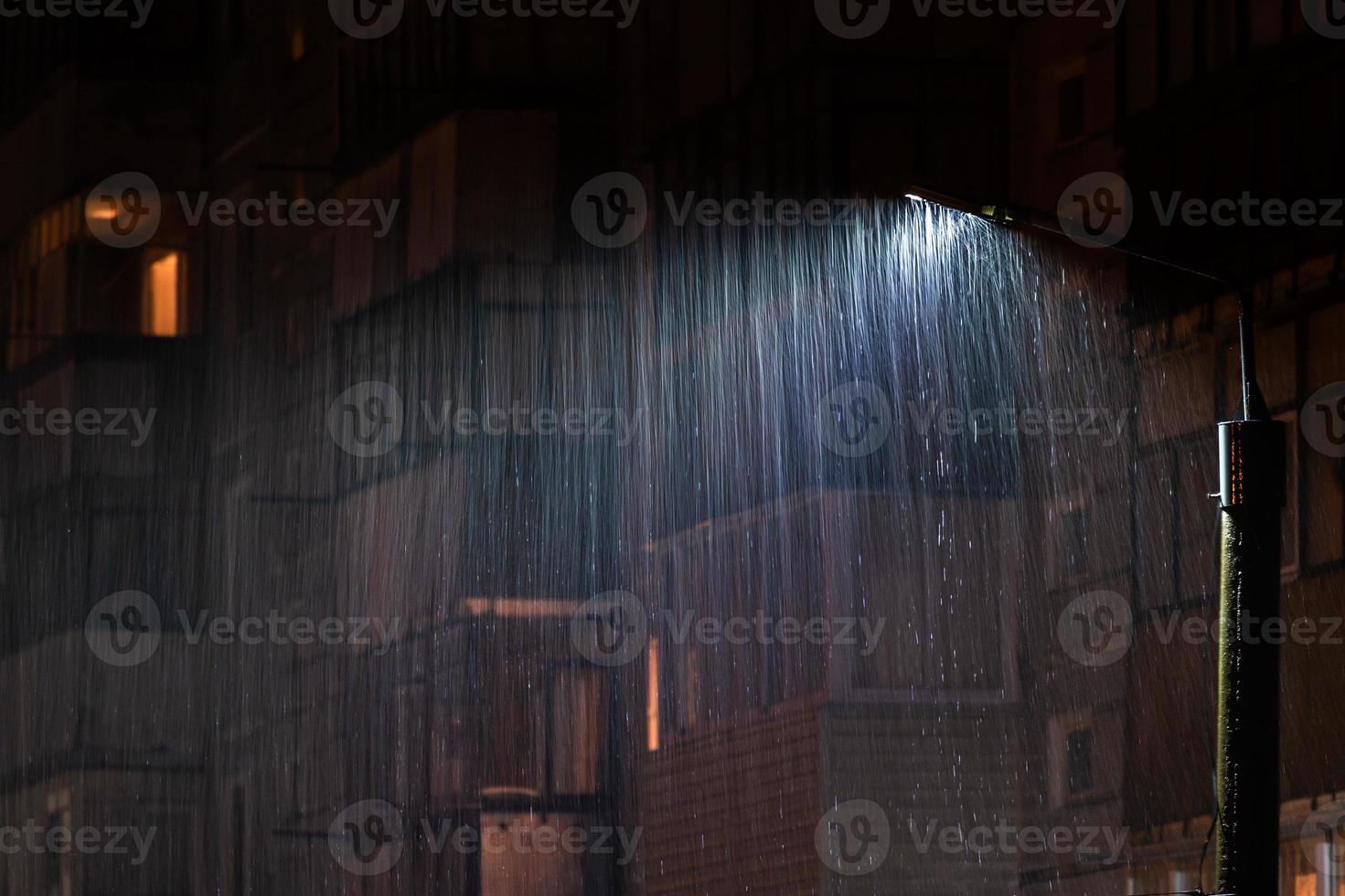 lamp post at rainy night with selective focus and long exposure motion blur of rain drops photo