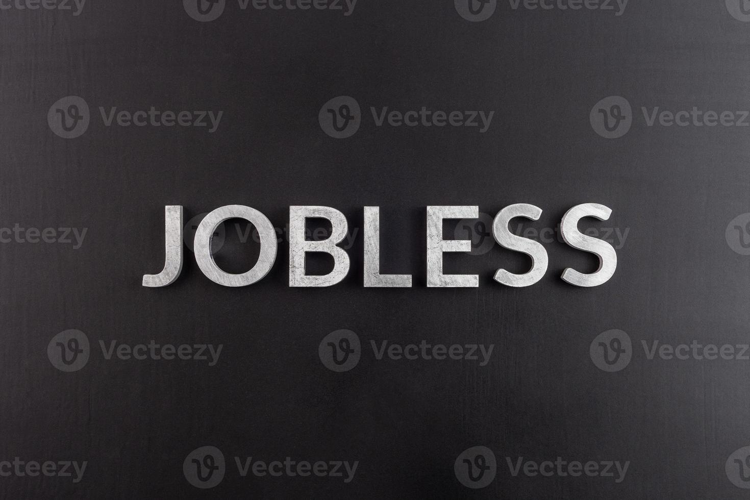 the word jobless laid with white scratched metal letters on flat black surface photo