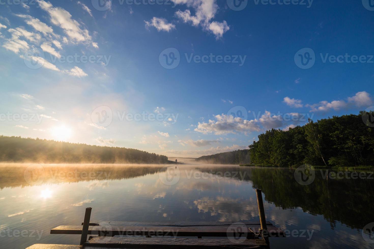 sunrise over the foggy river with a wooden pier photo