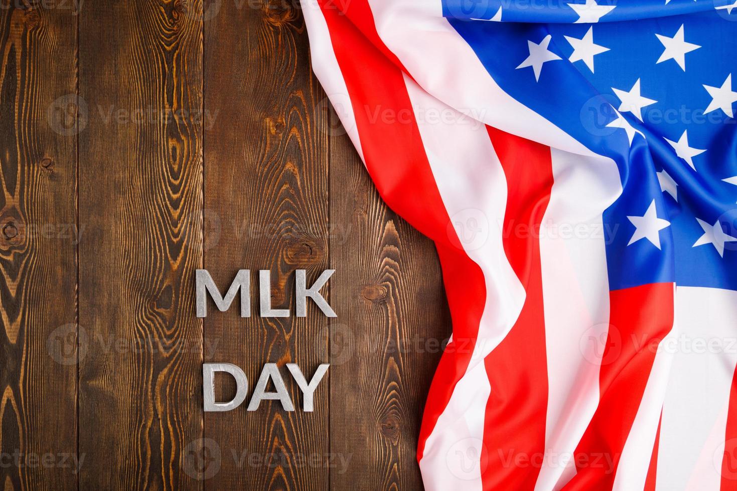 the word MLK day laid with silver metal letters on wooden surface with crumpled USA flag at right side photo