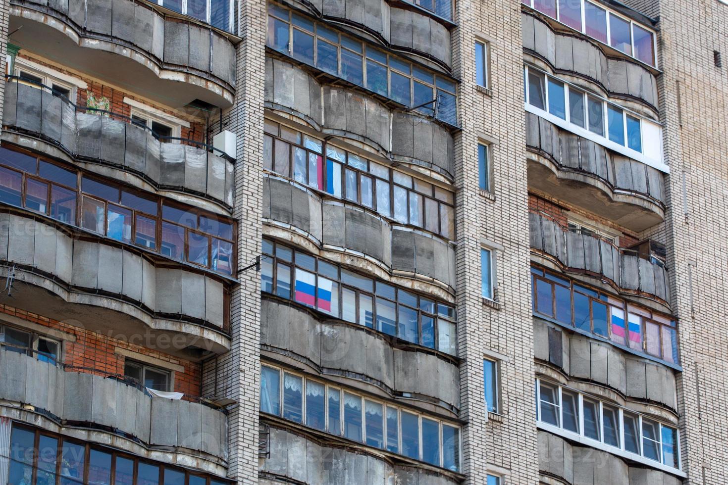 large russian apartment building balcony windows with russian tricolor flags photo