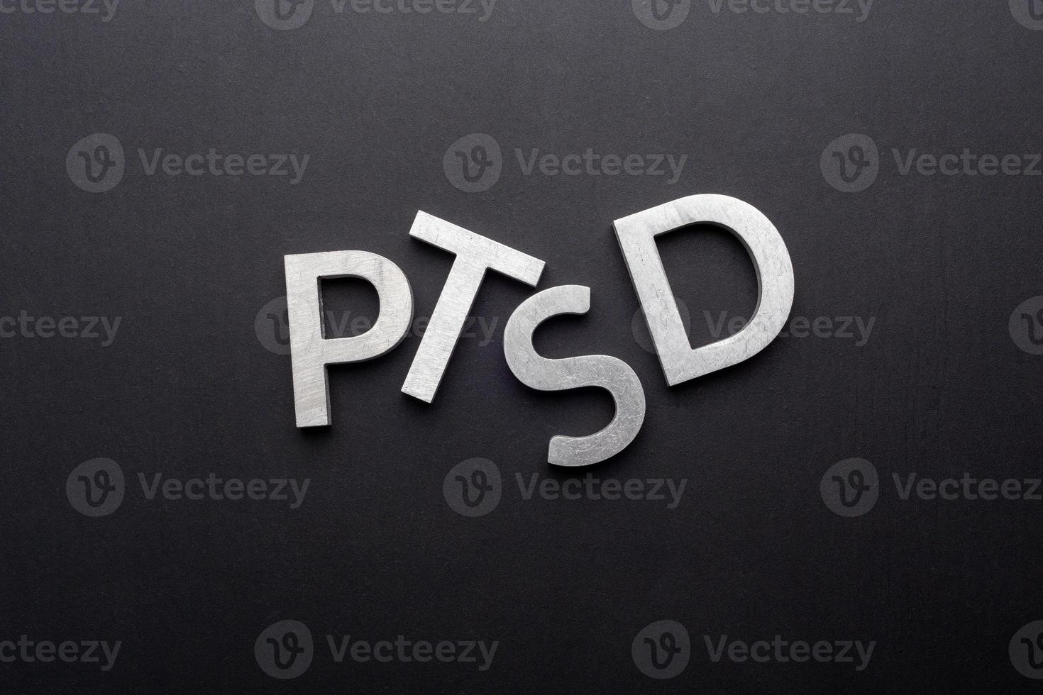 the word PTSD laid with silver metal letters on flat black background in directly above perspective photo