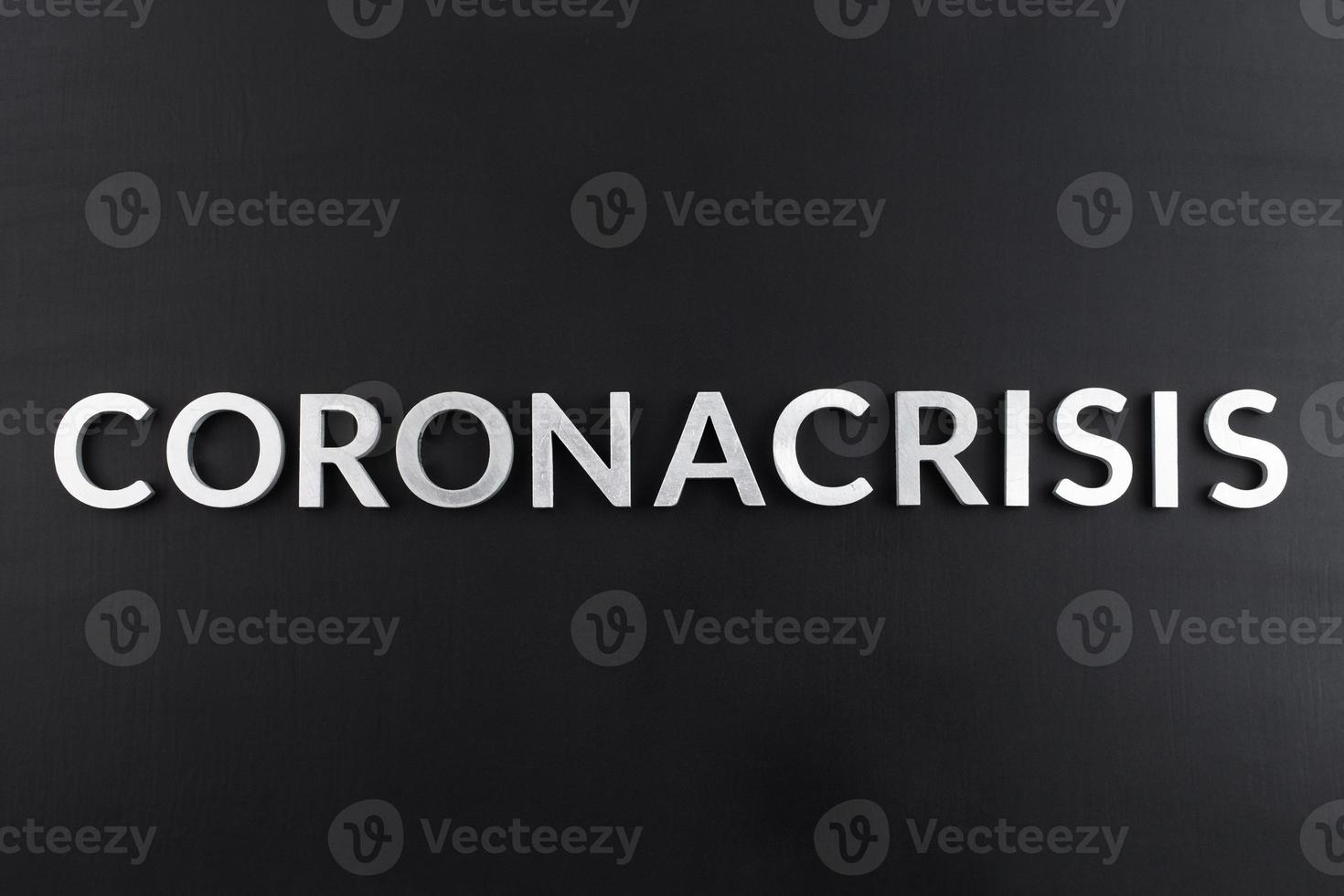 the word coronacrisis laid with white brushed metal letters on flat black surface photo