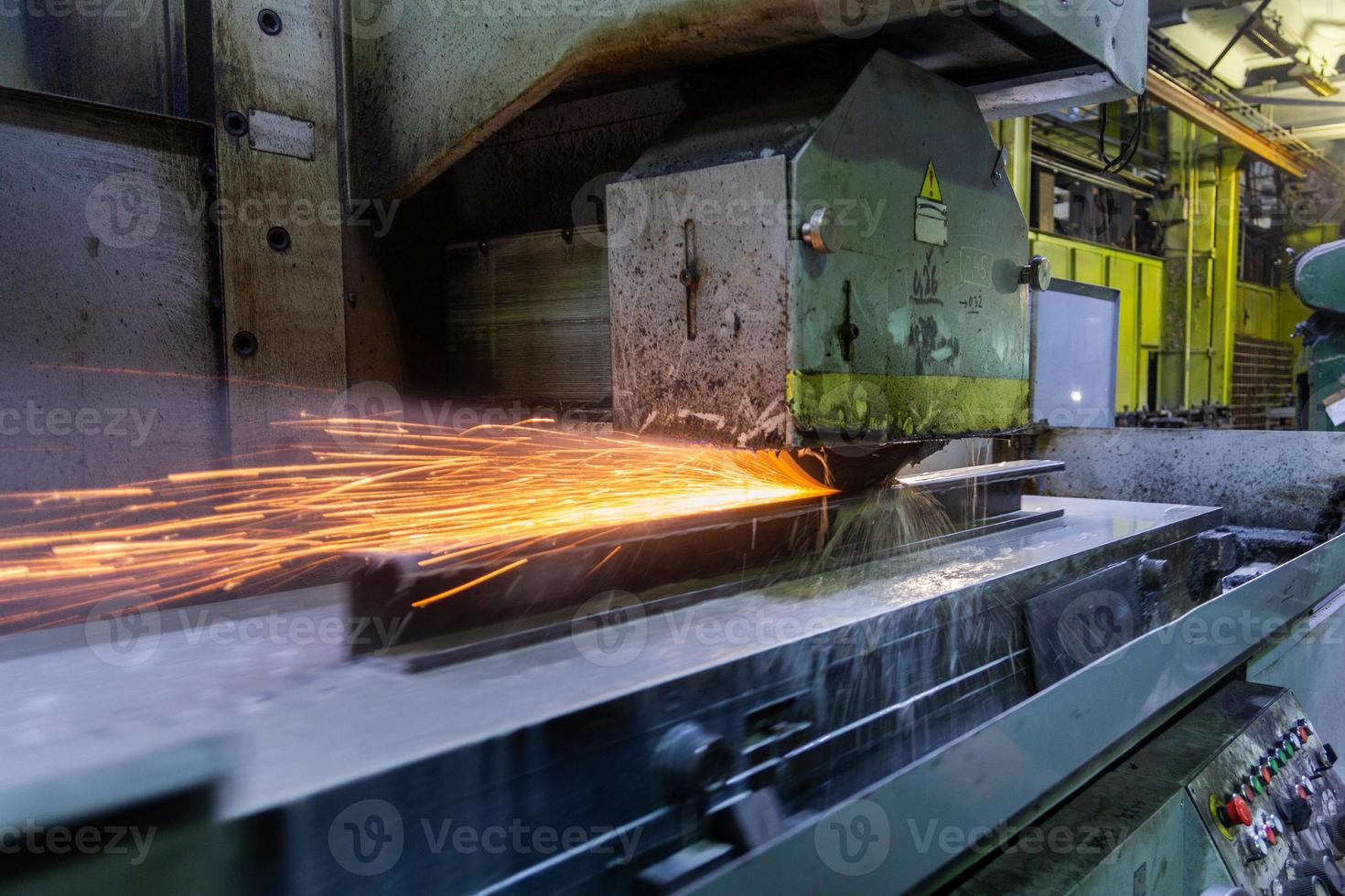 a process of flat surface grinding with a lot of sparks and liquid cooling indoors at metalworking shop photo