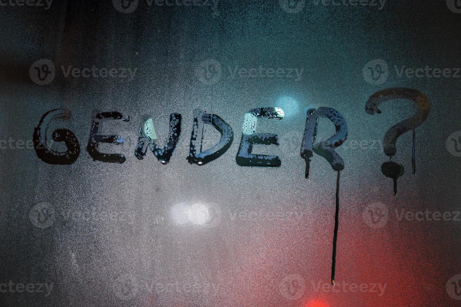 the question gender written by finger on night wet glass with blurred lights in background photo