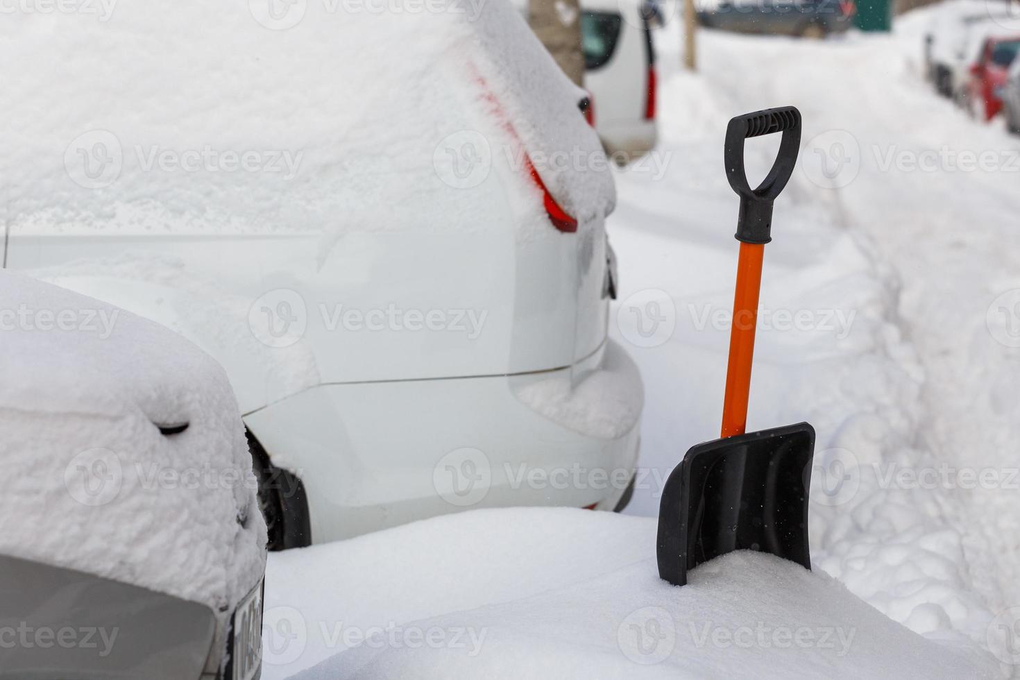 small plastic snow shovel near snow-covered cars at sunny winter morning photo