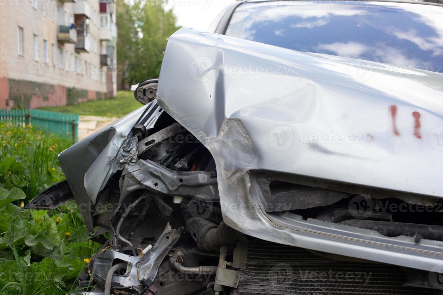 close-up view on silver car physically damaged in road accident, close-up with blurry background photo