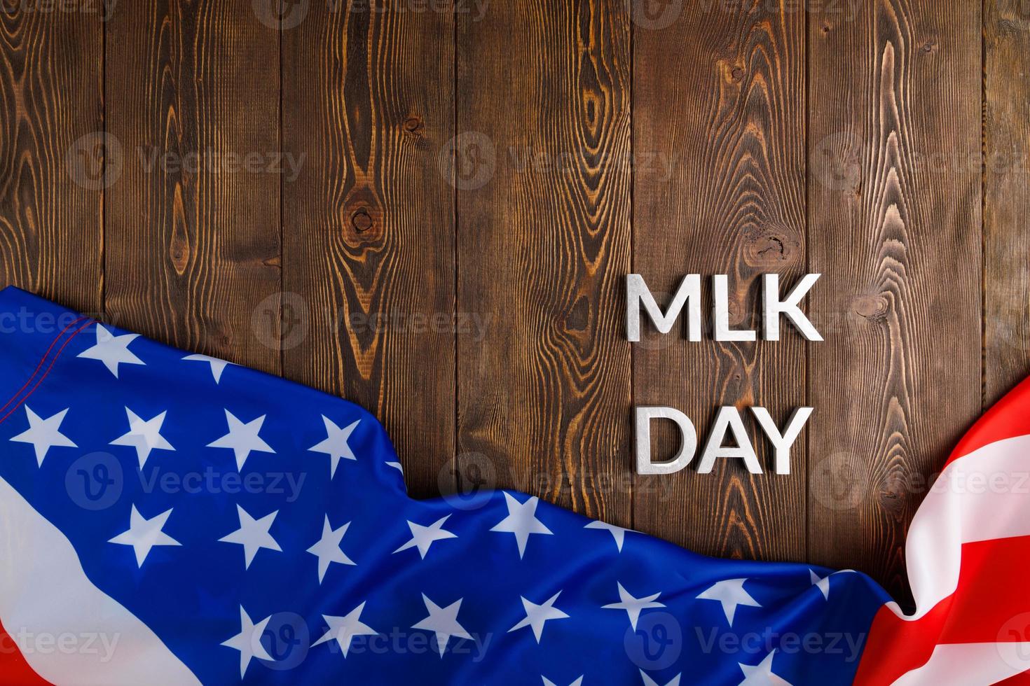 the word MLK day laid with silver metal letters on wooden surface with crumpled USA flag at lower side photo
