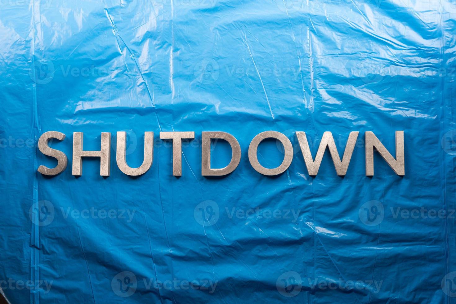 the word shutdown laid with silver metal letters on crumpled blue
