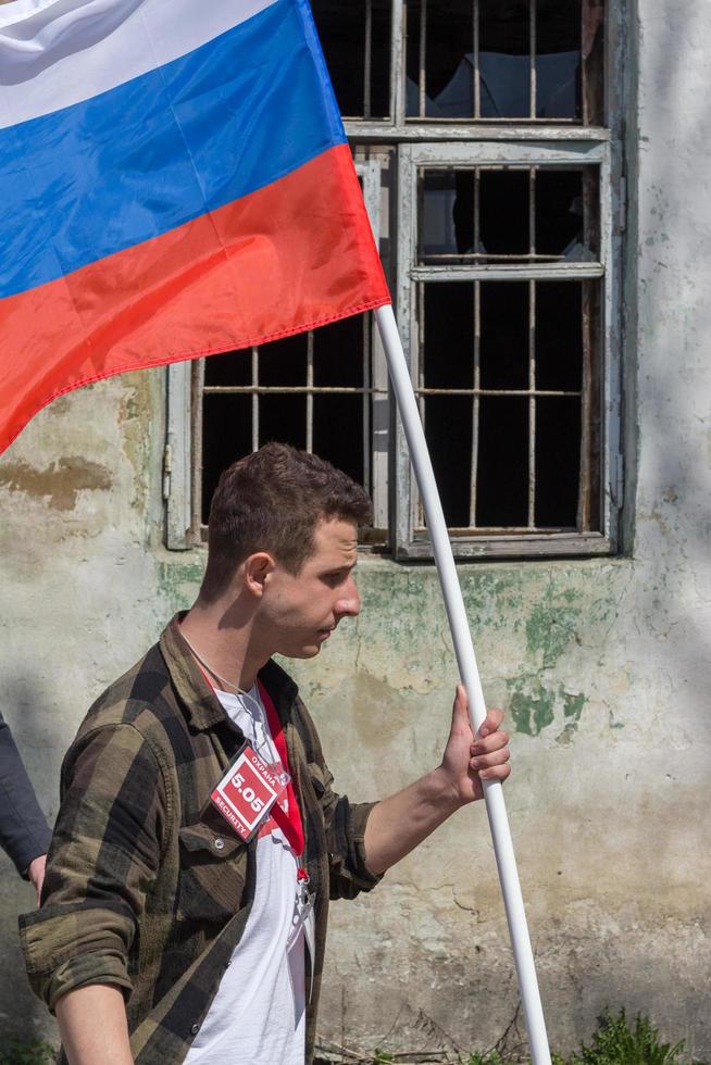 Man carrying russian tricolor flag in front of broken window with steel bars at political meeteing supporting Alexey Navalny photo