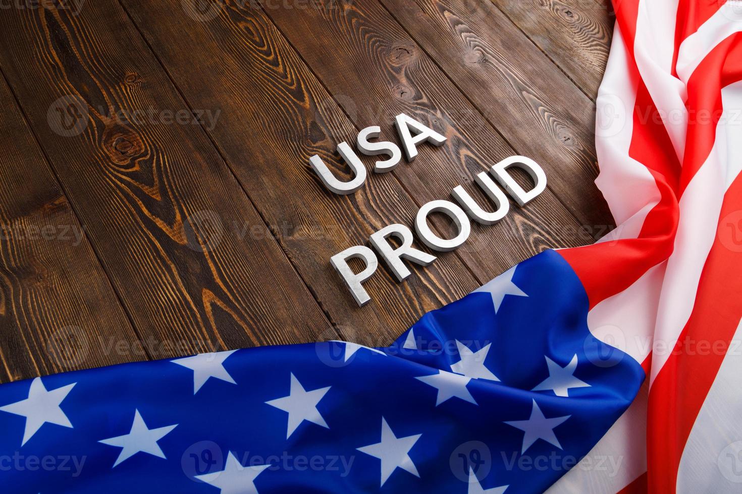 words USA proud laid with silver metal letters on brown wooden surface with flag of United States of America photo