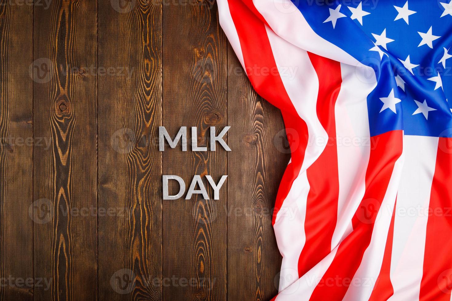 the word MLK day laid with silver metal letters on wooden surface with crumpled USA flag at right side photo