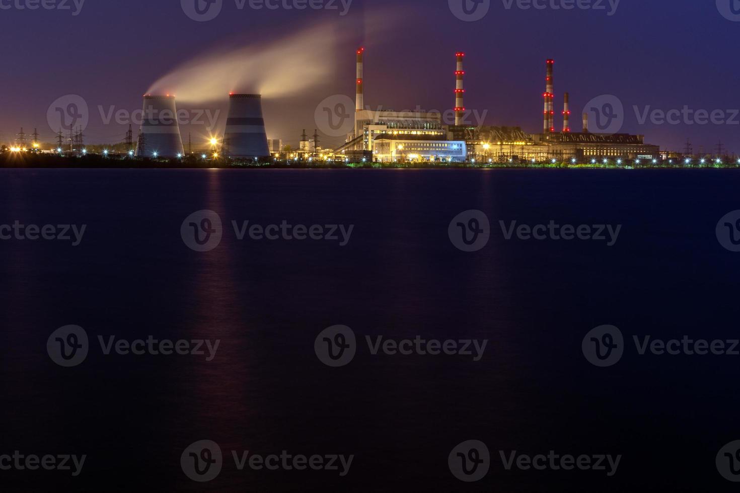 old thermal 450 megawatt power plant at night with artificial lake on foreground photo
