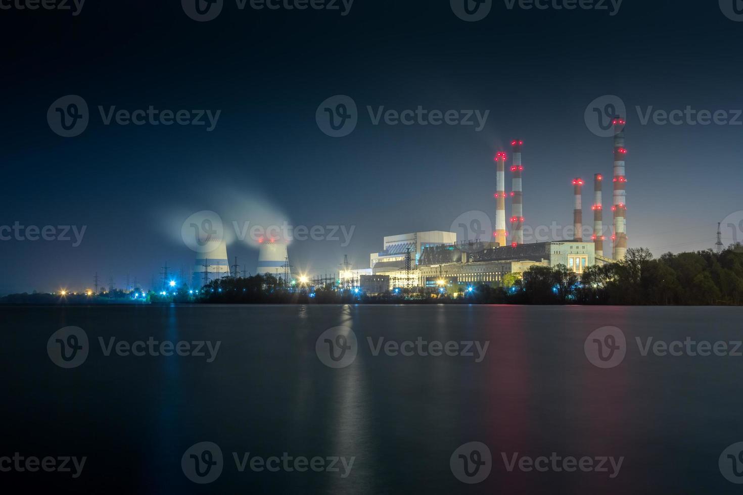 old thermal 450 megawatt power plant at night with artificial lake on foreground photo