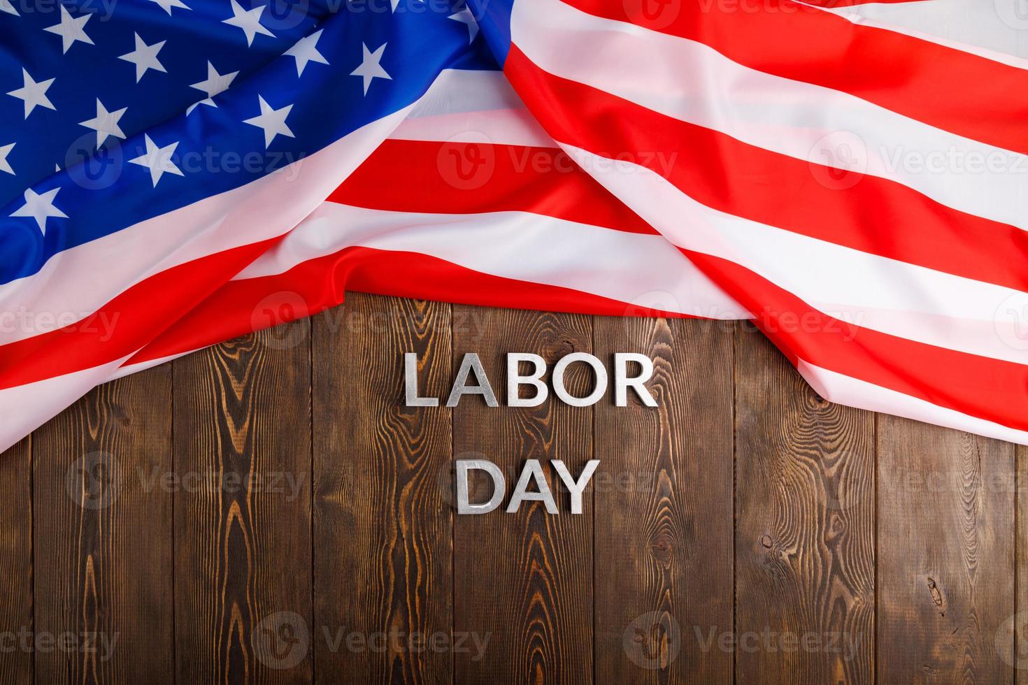 words labor day laid with silver metal letters on wooden surface with crumpled USA flag on upper side photo