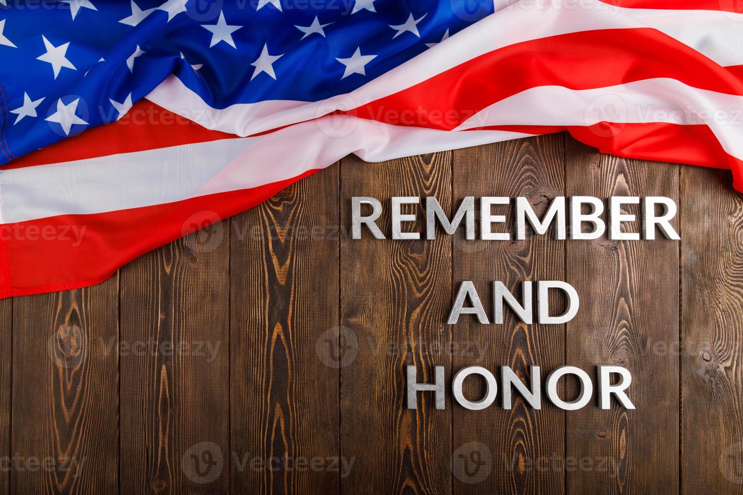 words remember and honor laid with silver metal letters on wooden background with USA flag above photo