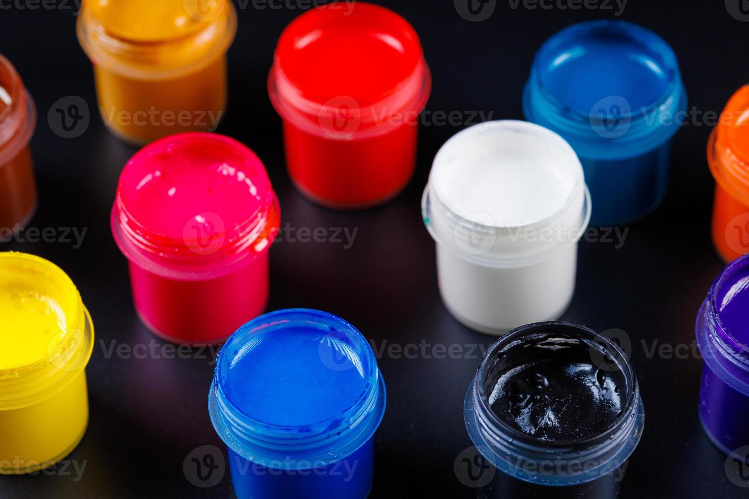 full-frame close-up view d of opened small gouache paint jars on black surface photo