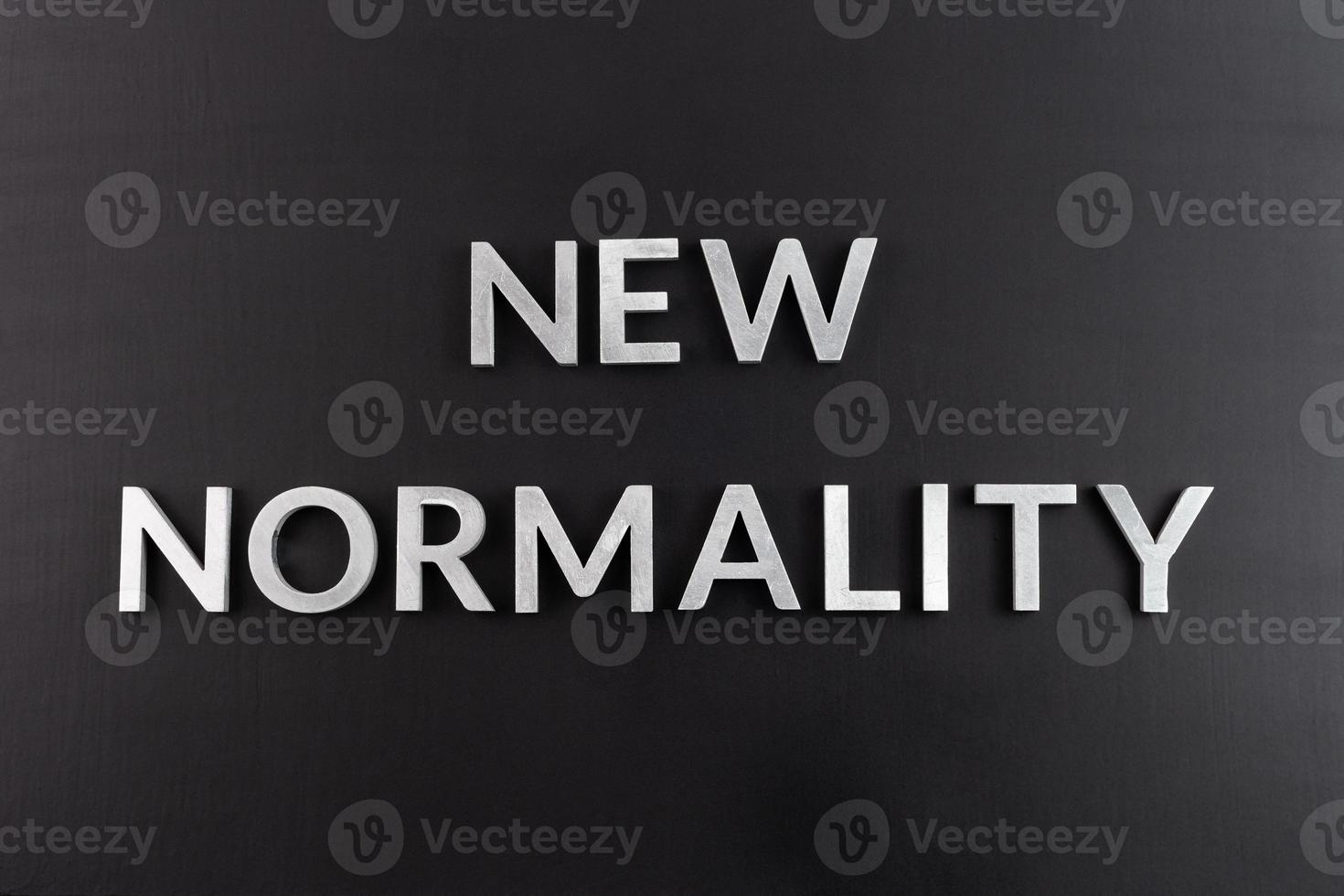 the words new normality laid with silver metal letters on flat black matte surface directly above in flat lay perspective photo
