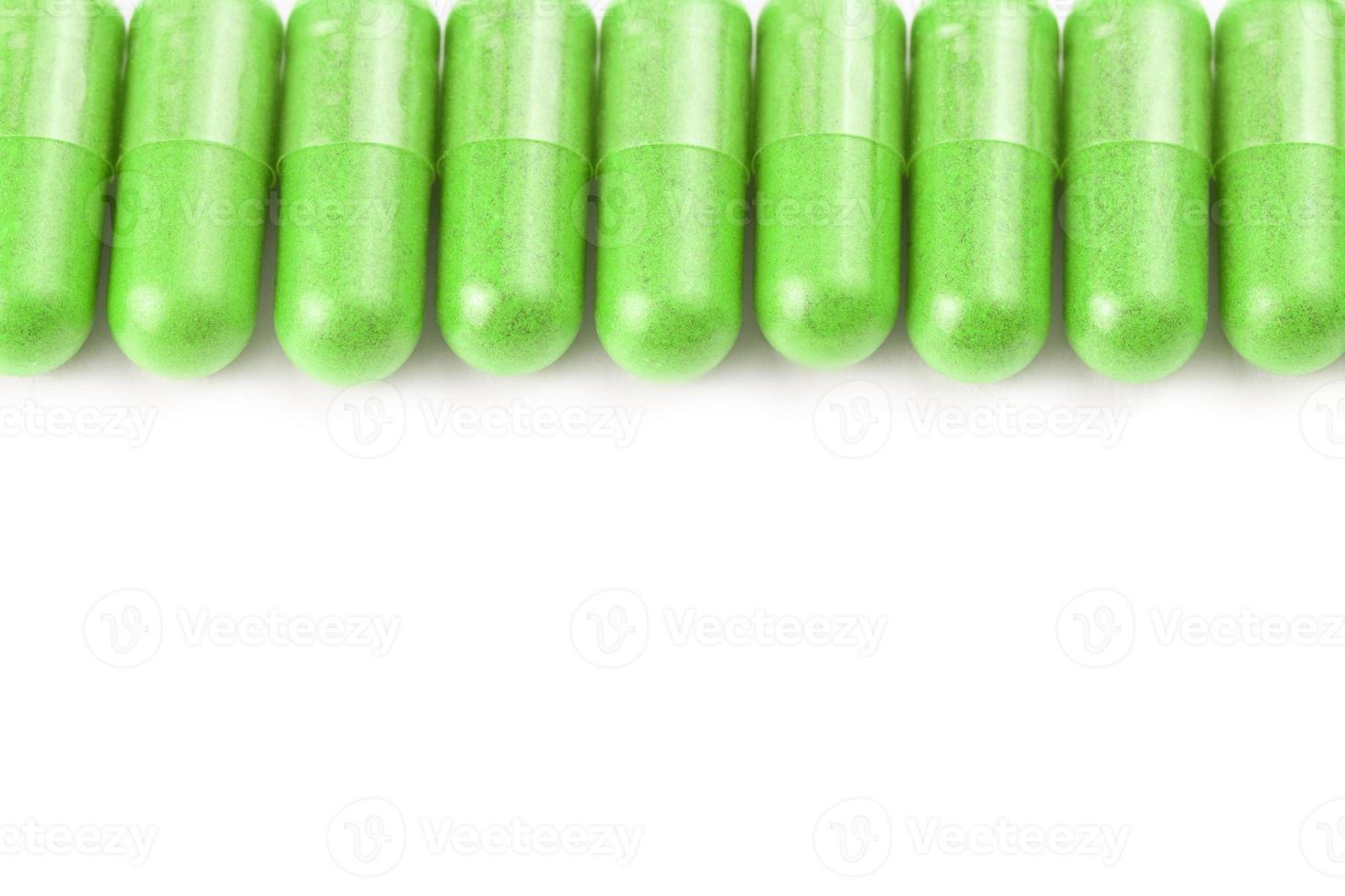 row of ufo green color organic capsules isolated on white background closeup with selective focus photo