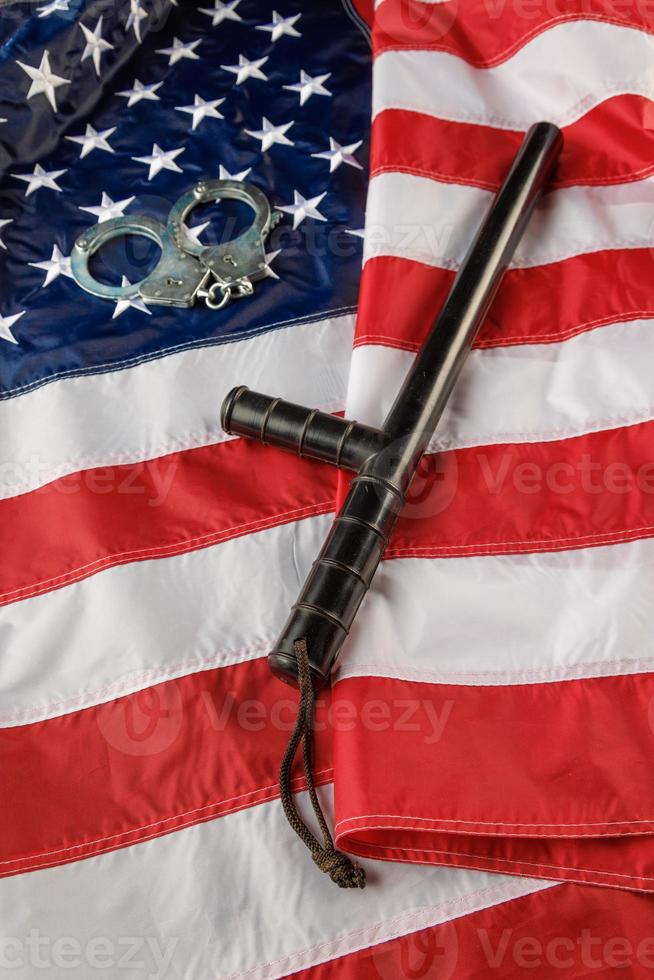 silver metal handcuffs and police nightstick over US flag on flat surface photo