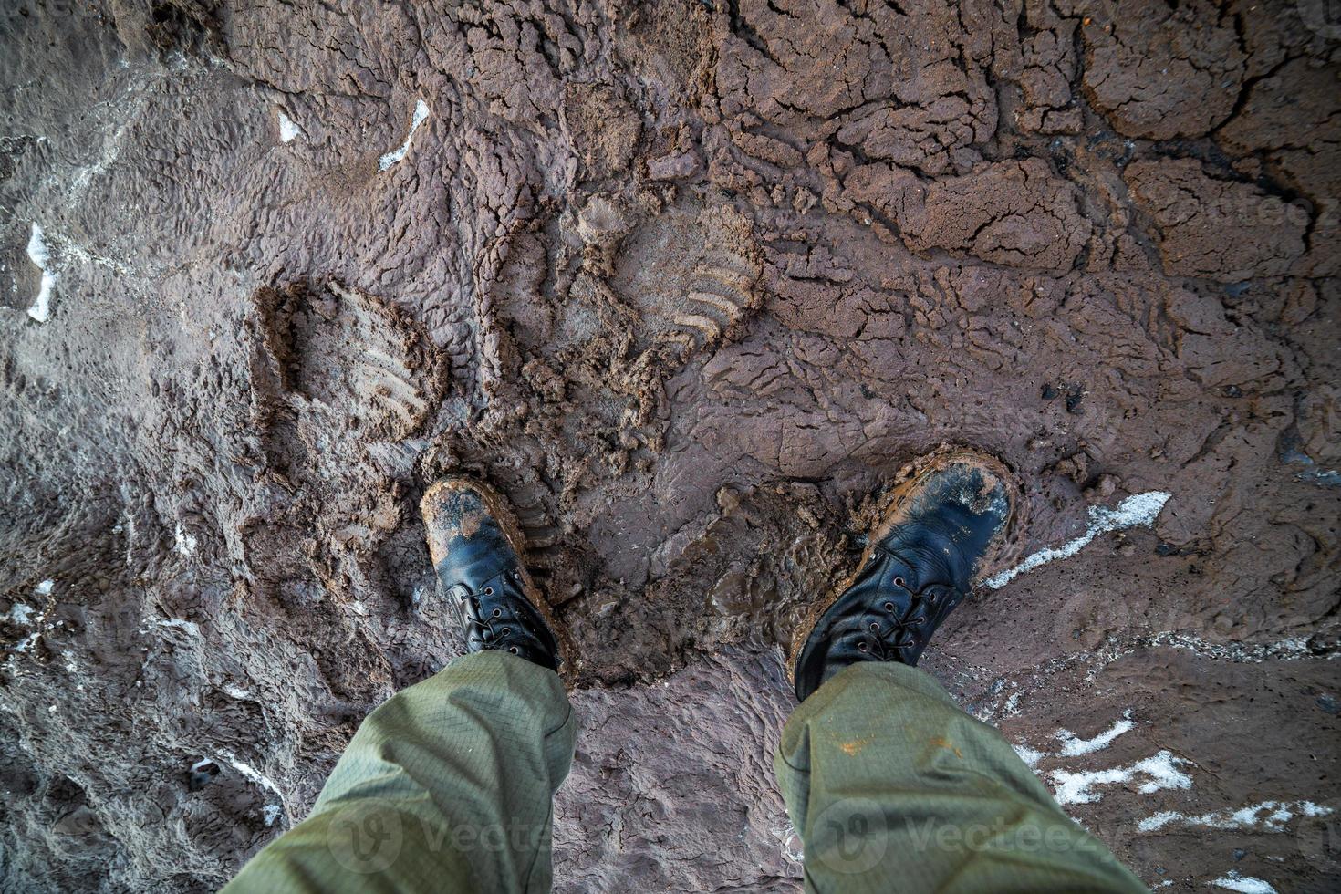 legs in army boots in wet mud closeup top-down vew with selective focus at daylight photo