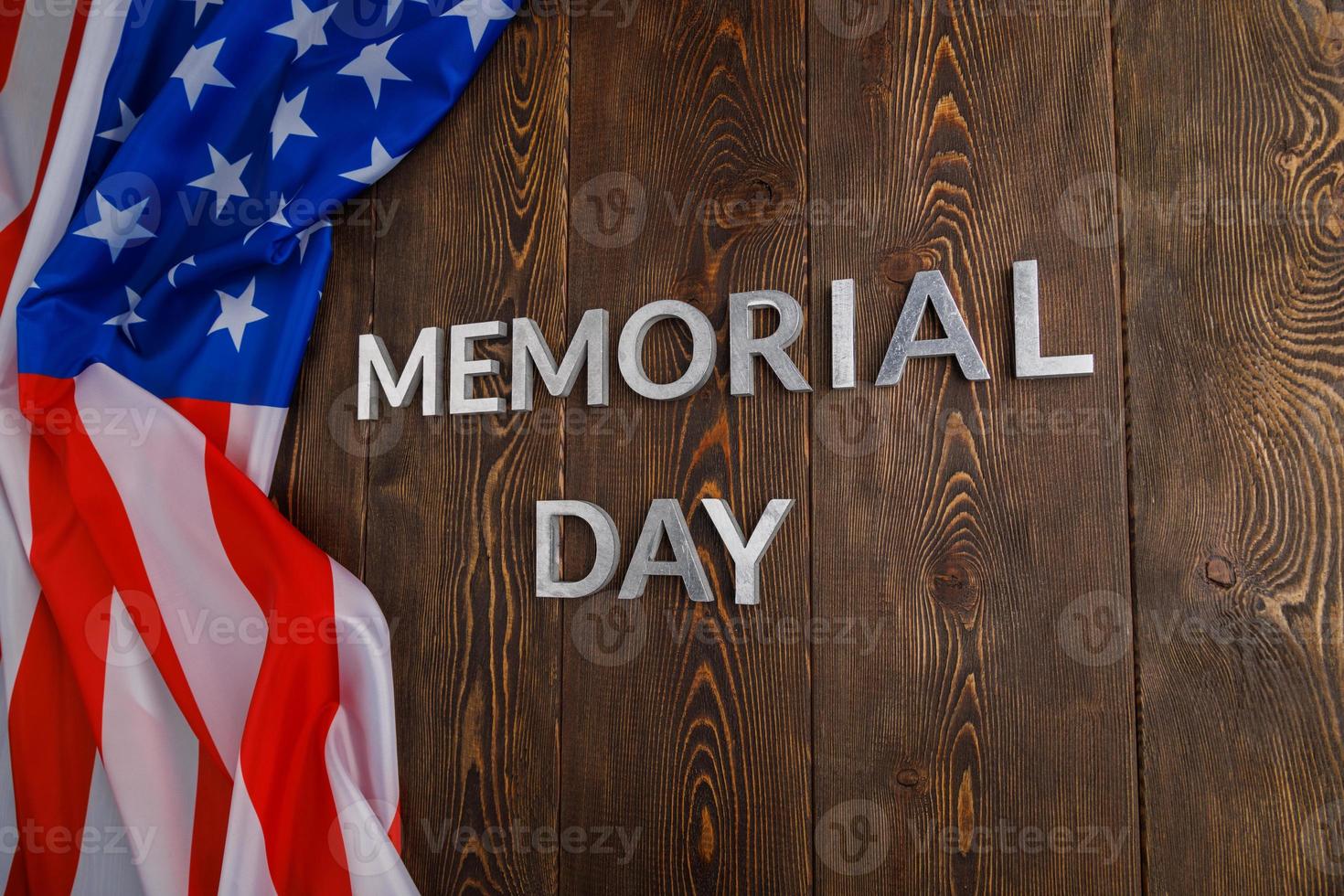 the words memorial day laid with silver metal letters on wooden board surface with crumpled usa flag photo
