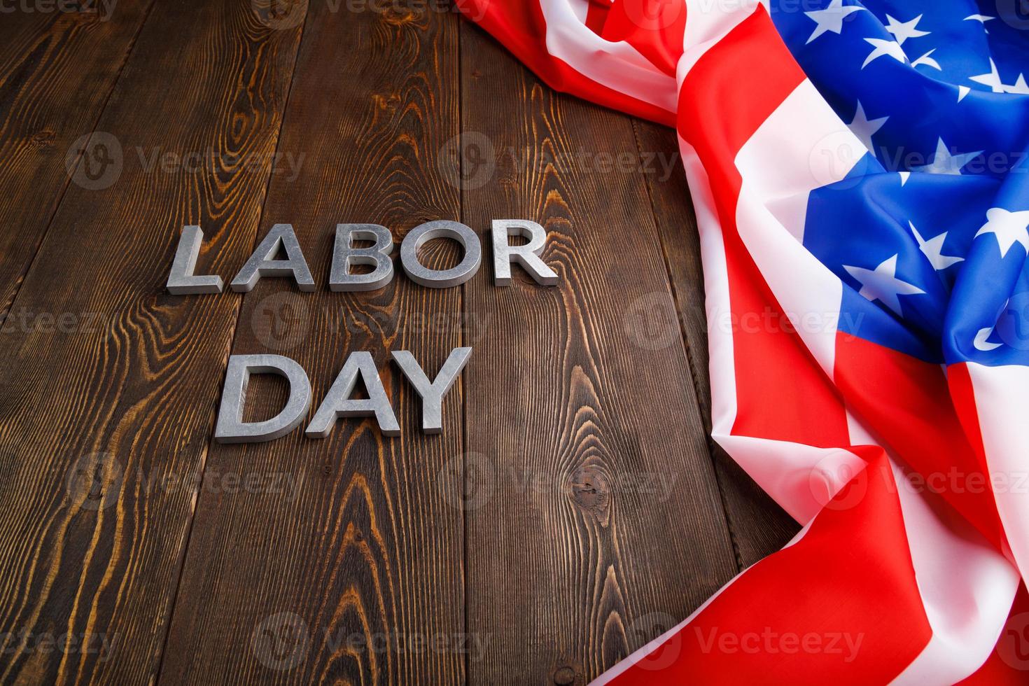 words labor day laid with silver metal letters on wooden surface with crumpled USA flag on left side photo