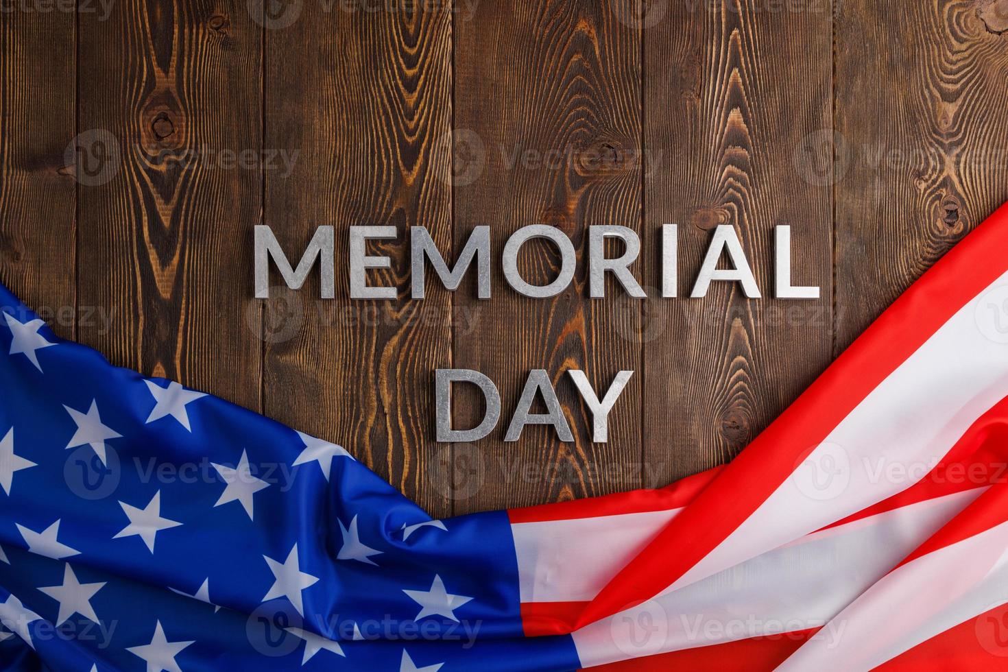 the words memorial day laid with silver metal letters on wooden board surface with crumpled usa flag photo