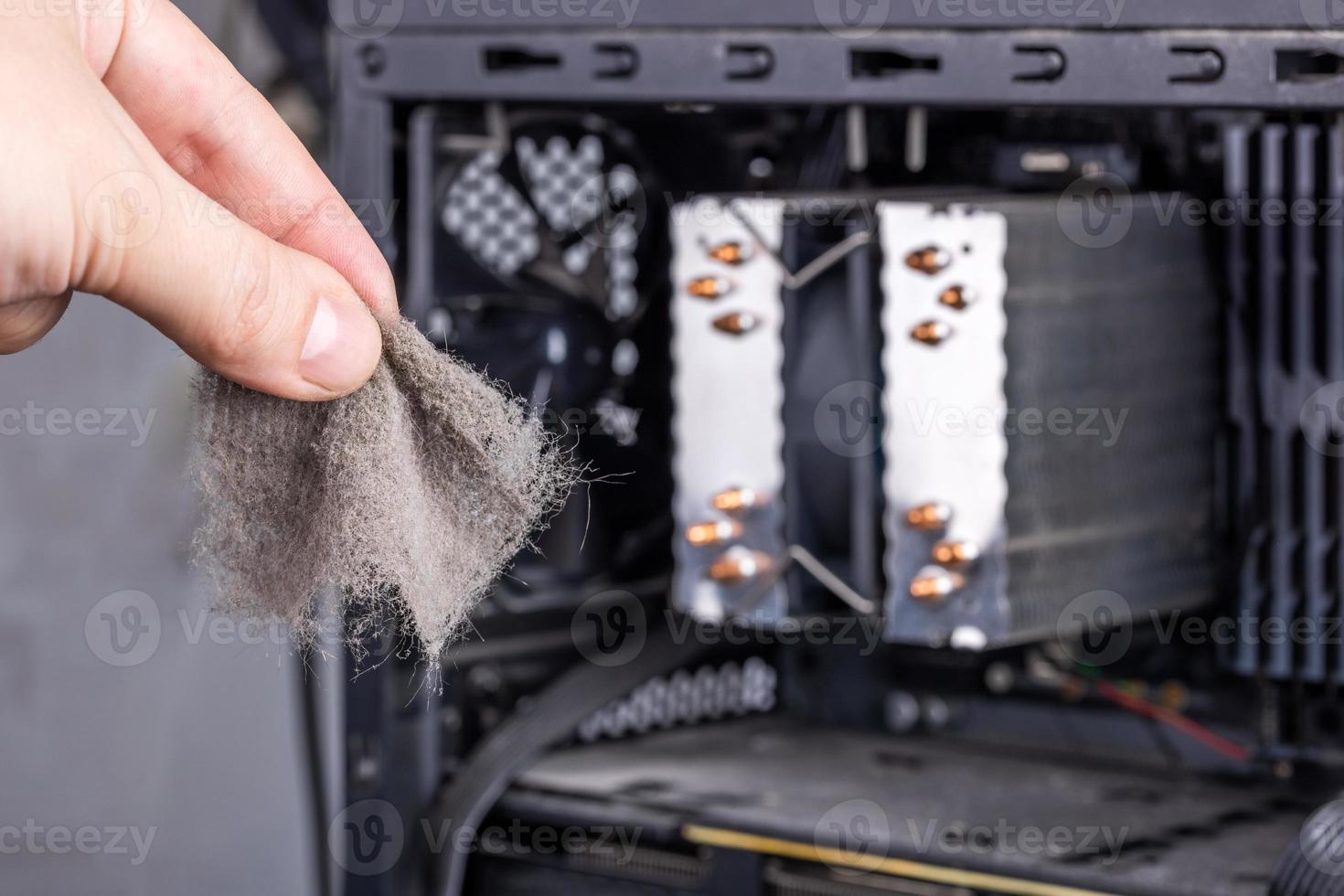bare caucasian hand holding dust clog in front of opened pc case during maintenance photo