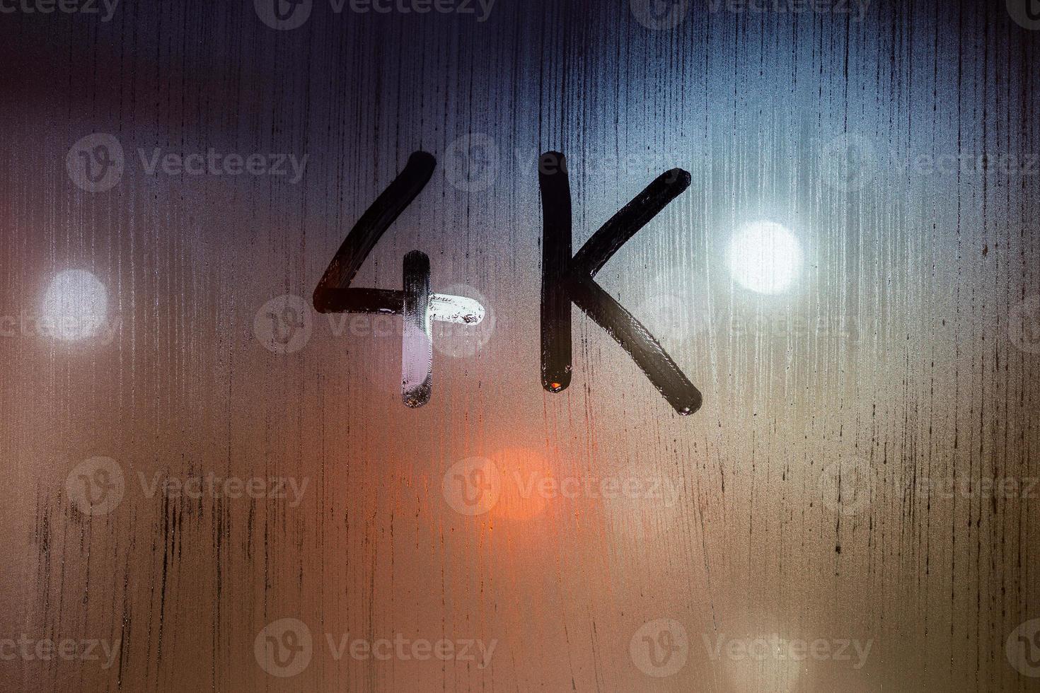 a handwritten word 4k on wet glass with blurred night lights in background photo