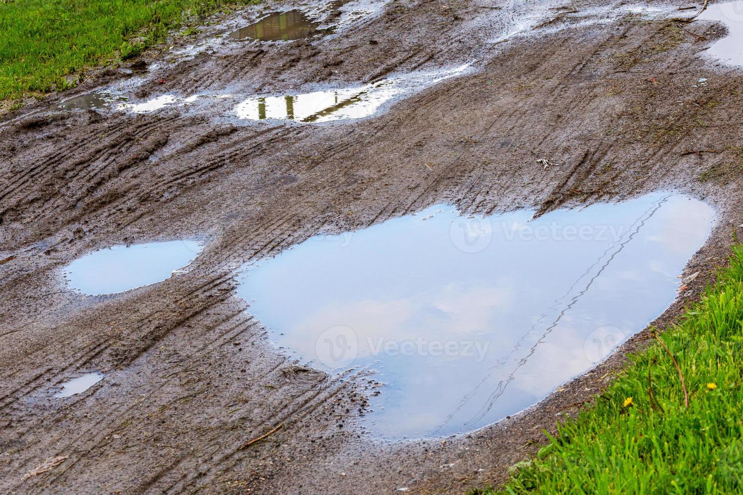 puddle in dirt road at summer daylight - closeup with selective focus, diagonal composition photo