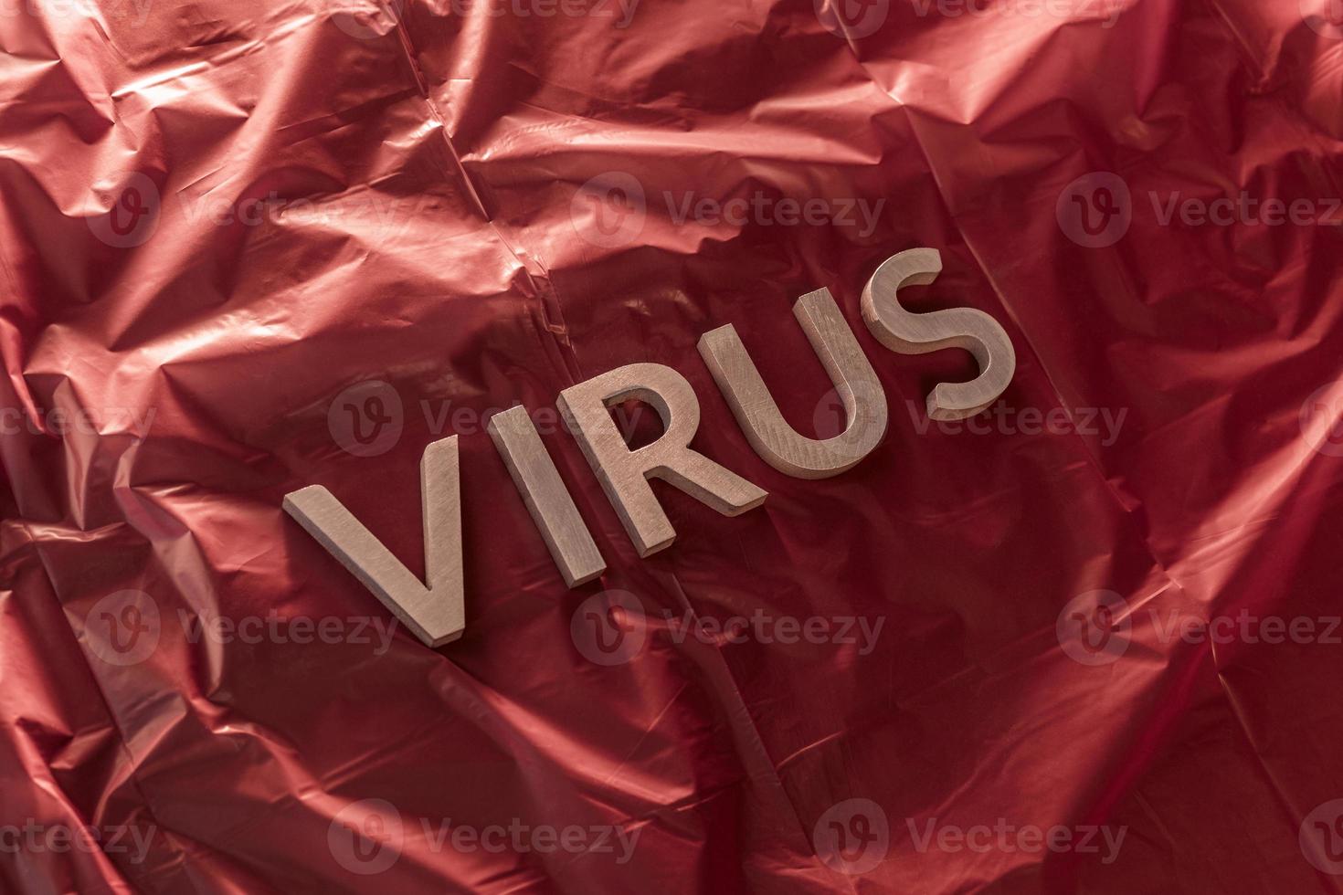 la palabra virus se colocó con letras de metal plateado en una película de plástico rojo arrugada con una luz dramática foto