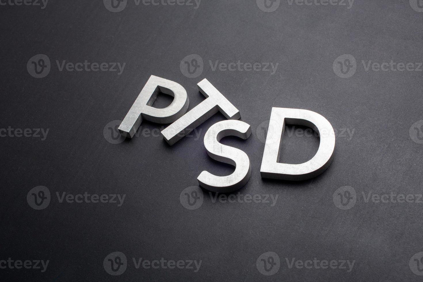 the word PTSD laid with silver metal letters on flat black background photo