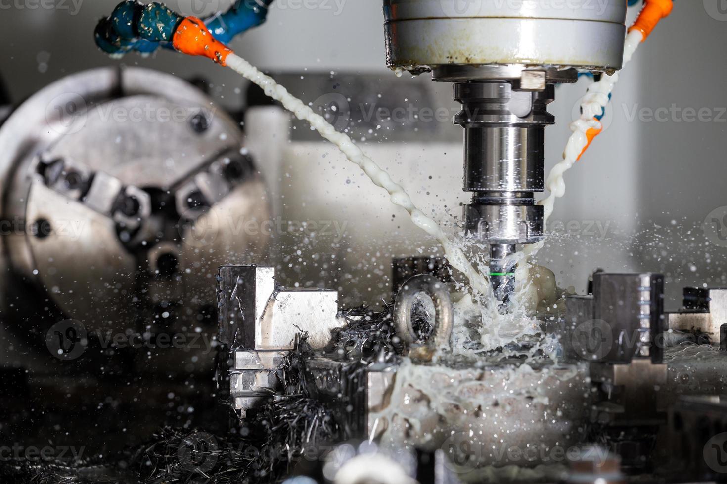 un proceso de fresado de acero cnc vertical con corrientes de refrigerante de agua externas, salpicaduras y muchas virutas de metal foto