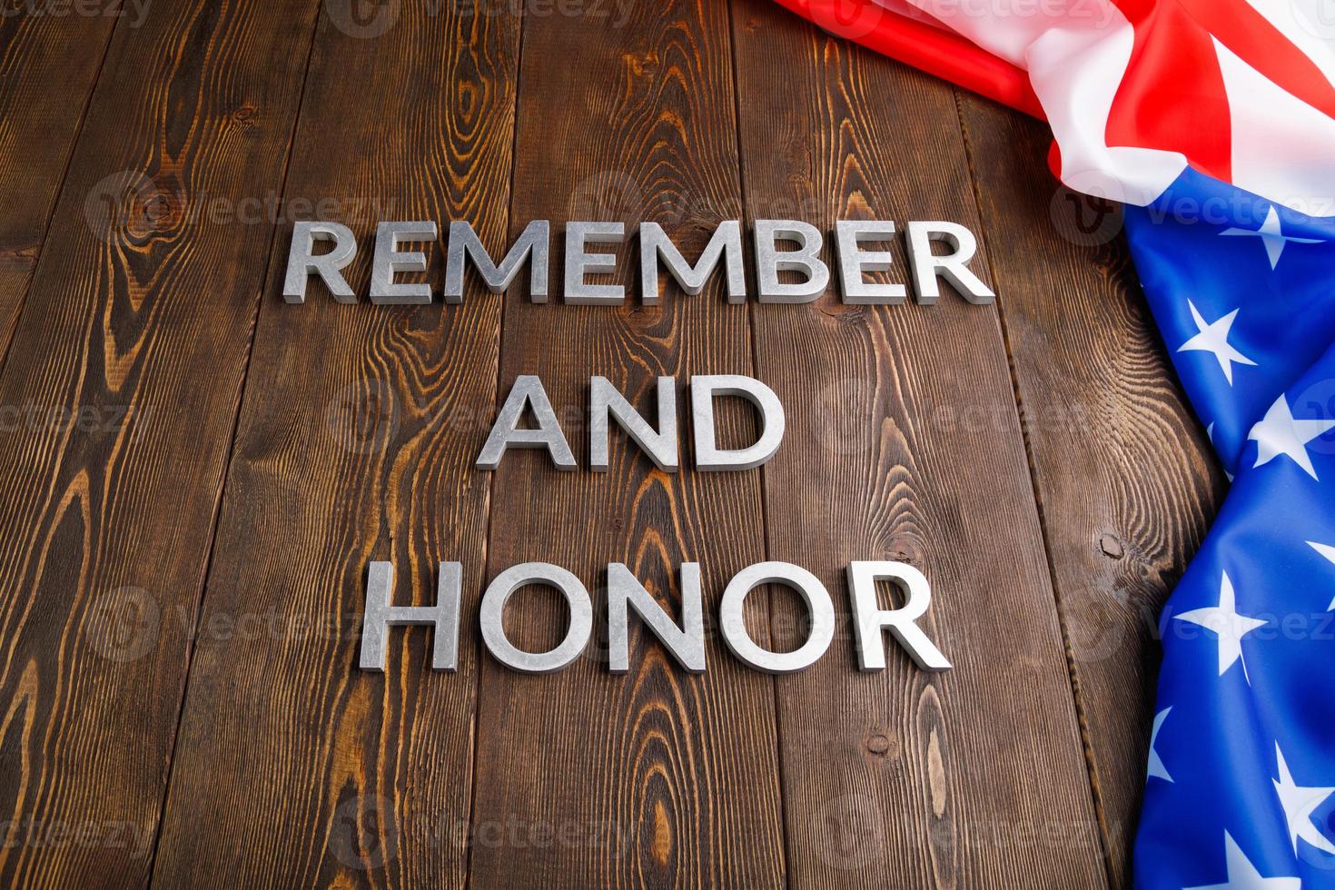 words remember and honor laid with silver metal letters on wooden background with USA flag on the right side photo