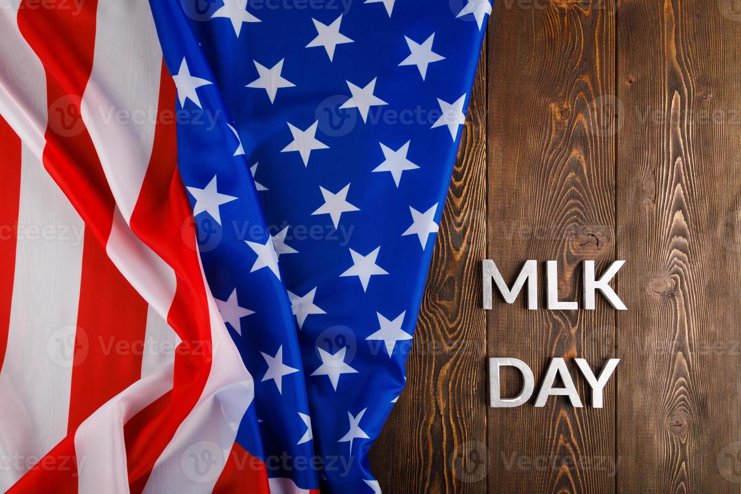 the word MLK day laid with silver metal letters on wooden surface with crumpled USA flag at left side photo