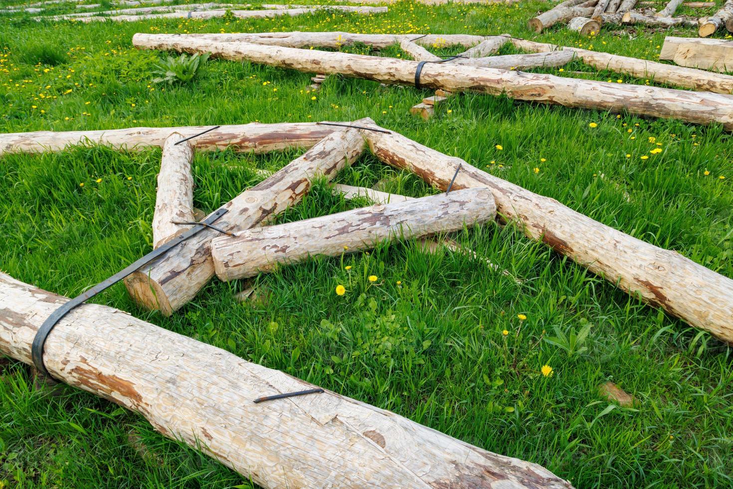conexión de banda de acero forjado de vigas de troncos de madera para el marco de la viga de soporte del techo colocado sobre hierba verde en el día de verano foto