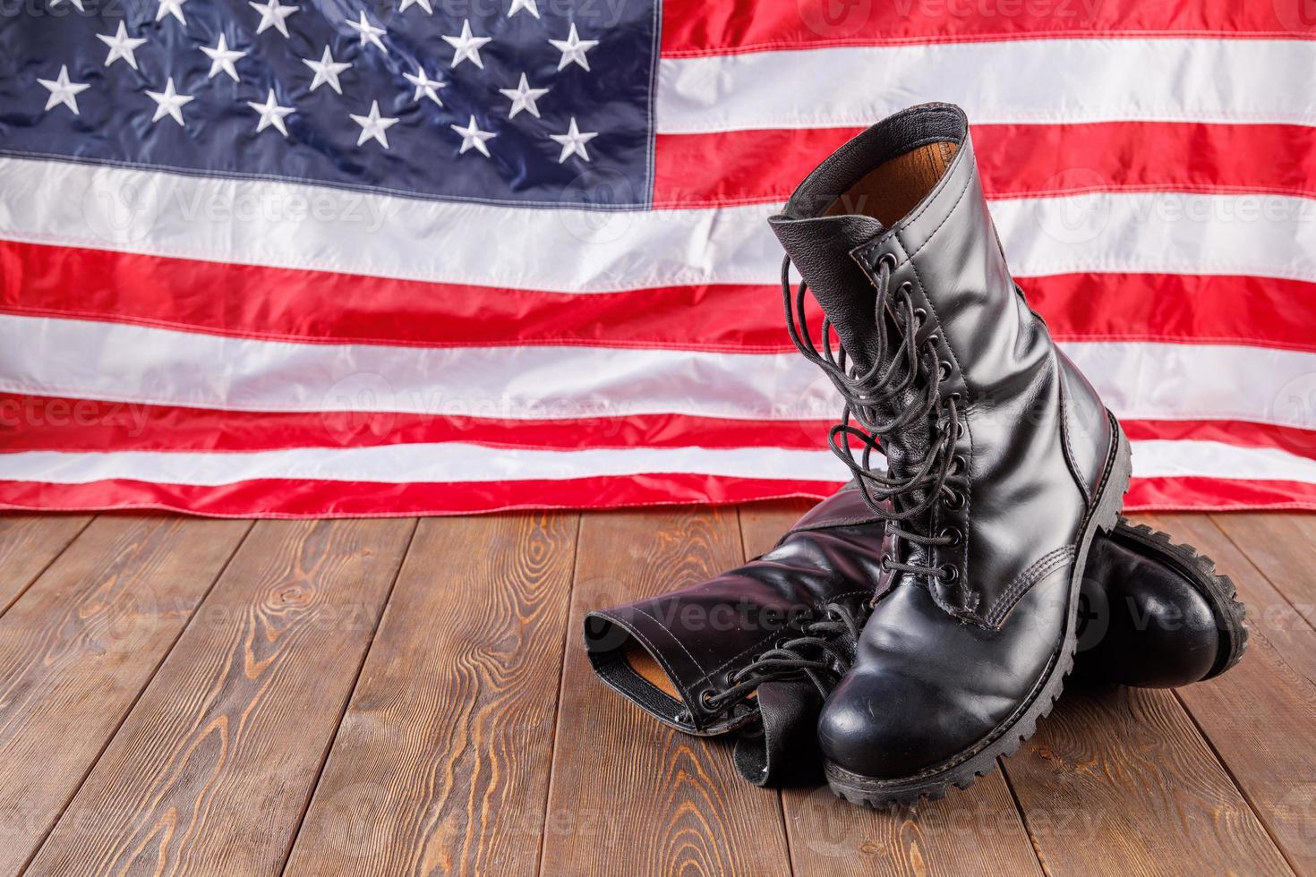 black ankle boots in front of US flag on wooden surface photo
