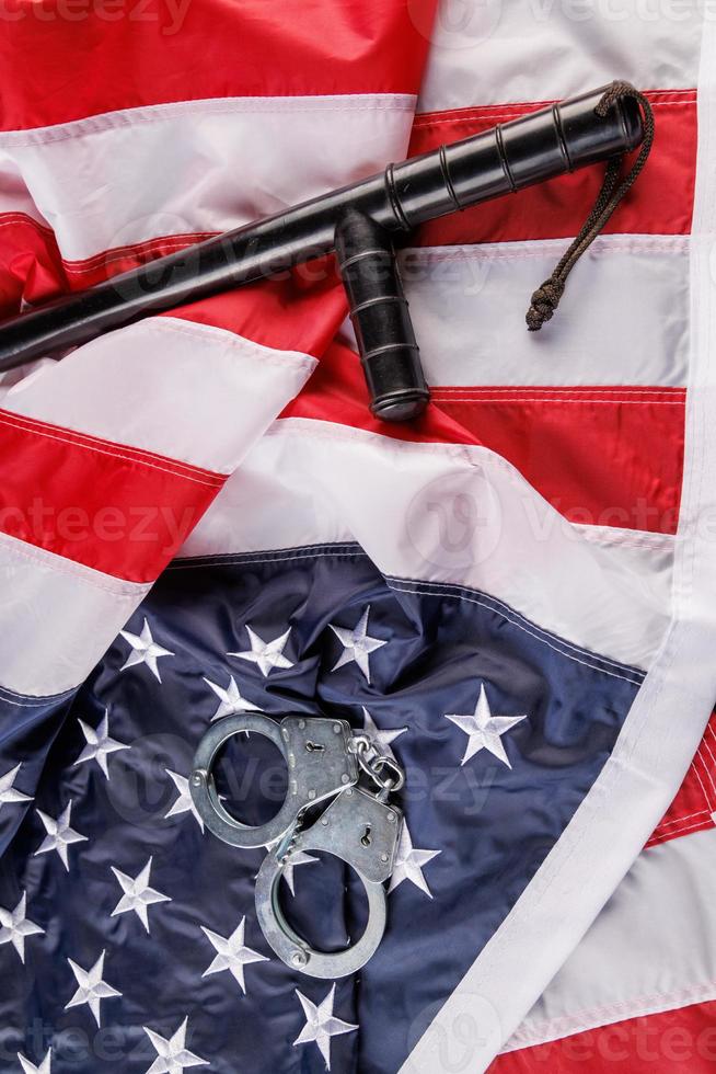 silver metal handcuffs and police nightstick over US flag on flat surface photo